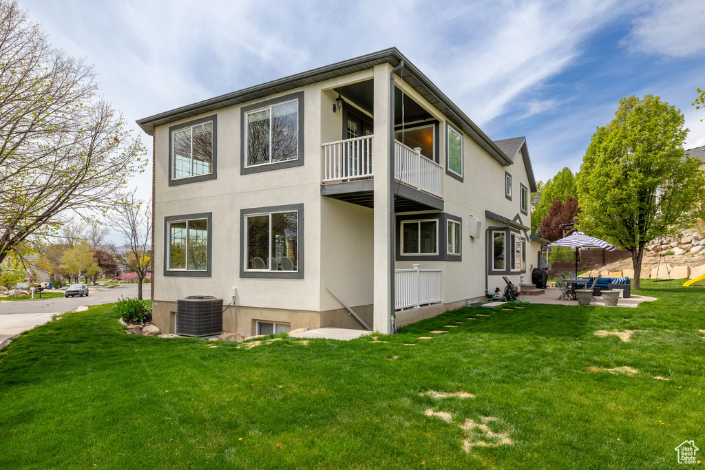 Back of property with cooling unit, an outdoor hangout area, stucco siding, and a balcony