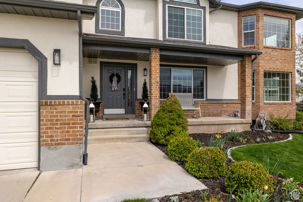 View of exterior entry with a porch, brick siding, and stucco siding