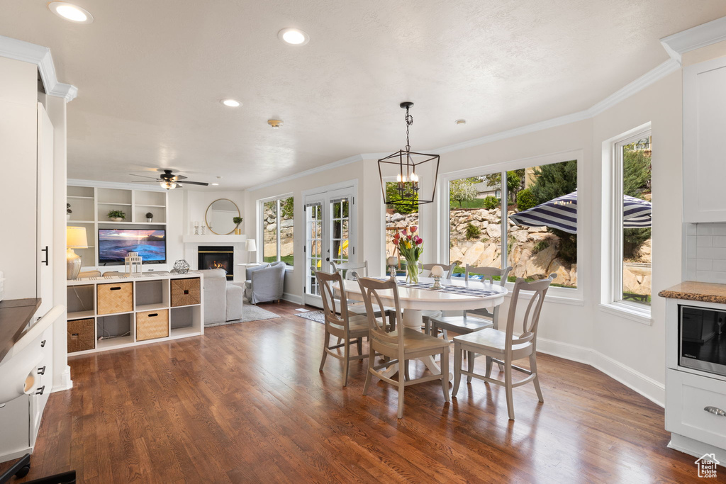 Dining space featuring baseboards, recessed lighting, dark wood-type flooring, and a lit fireplace