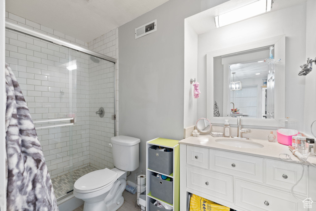 Bathroom with toilet, visible vents, vanity, and a stall shower