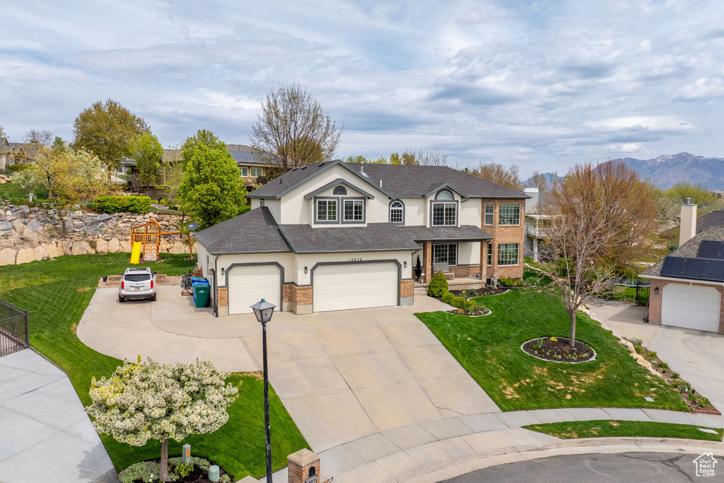 Traditional home with fence, a front lawn, stucco siding, concrete driveway, and roof with shingles