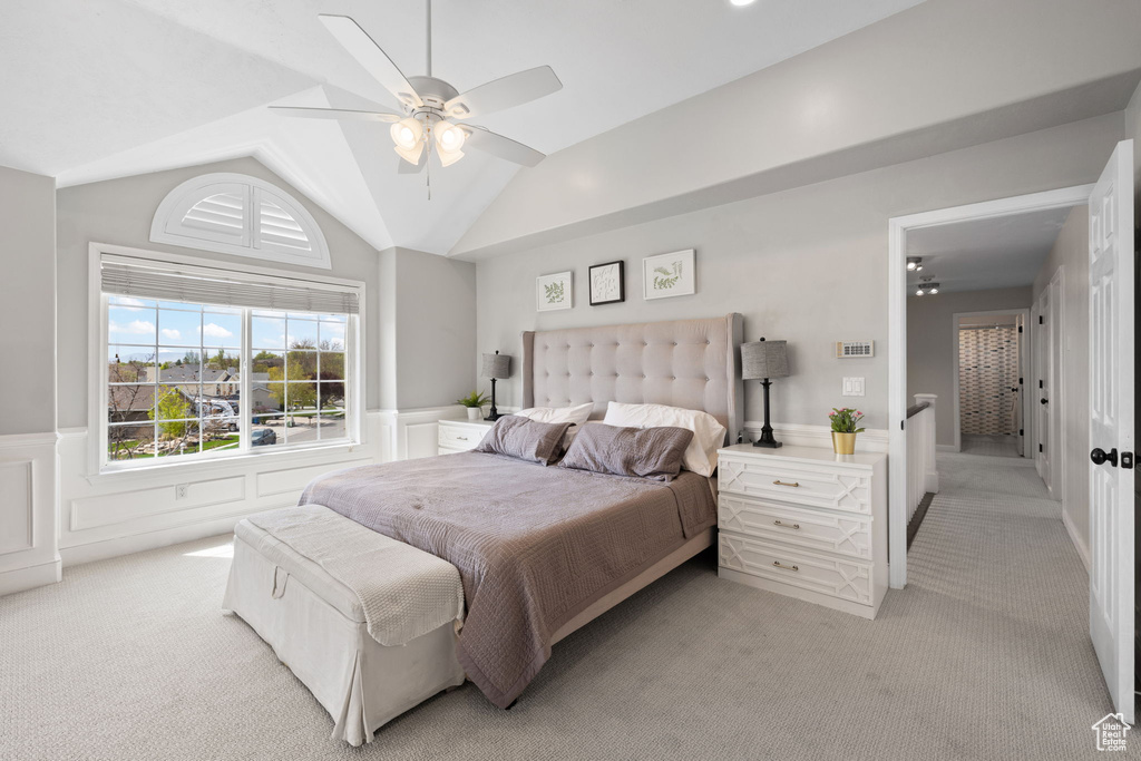 Bedroom with lofted ceiling, a wainscoted wall, and light colored carpet