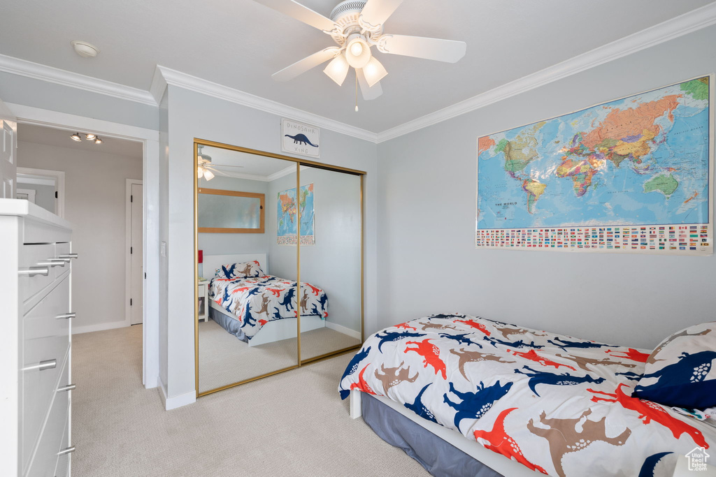 Carpeted bedroom featuring ceiling fan, baseboards, ornamental molding, and a closet