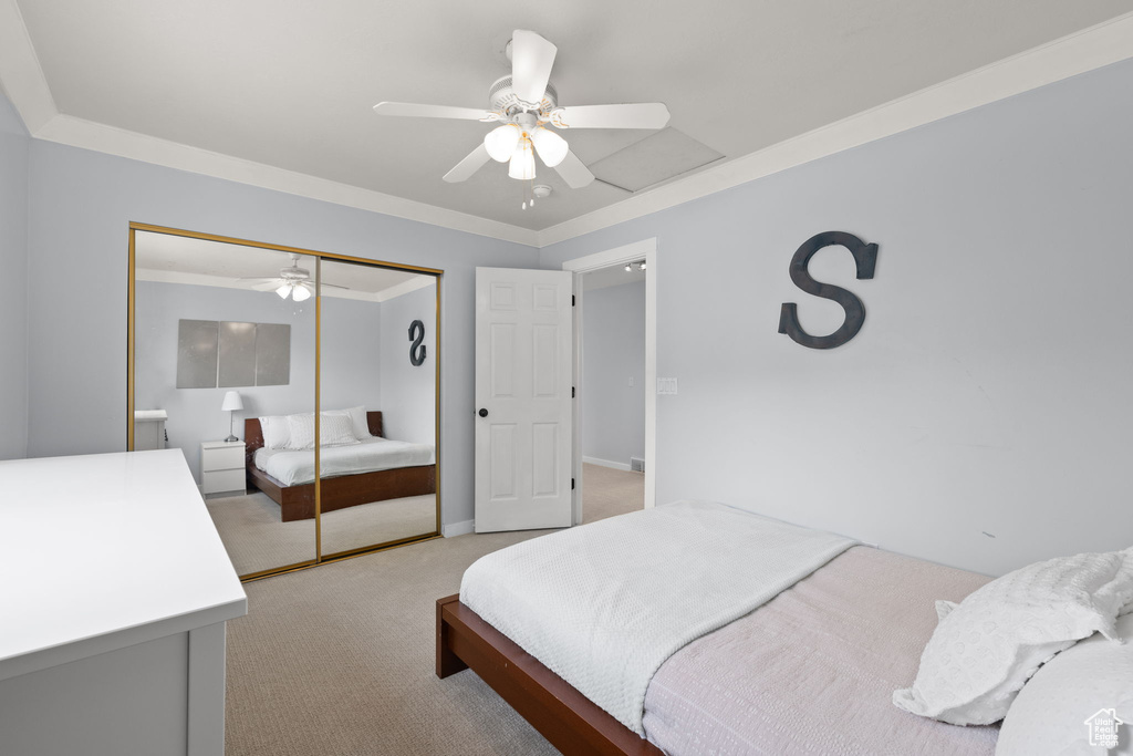 Bedroom featuring a ceiling fan, a closet, light colored carpet, baseboards, and ornamental molding
