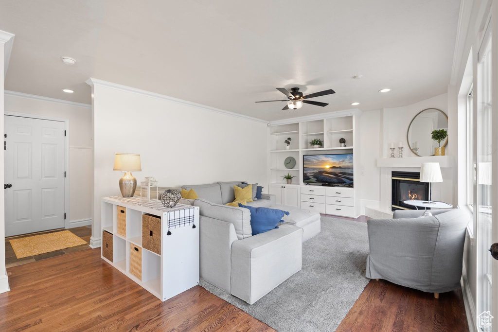 Living room featuring a glass covered fireplace, recessed lighting, a ceiling fan, wood finished floors, and crown molding