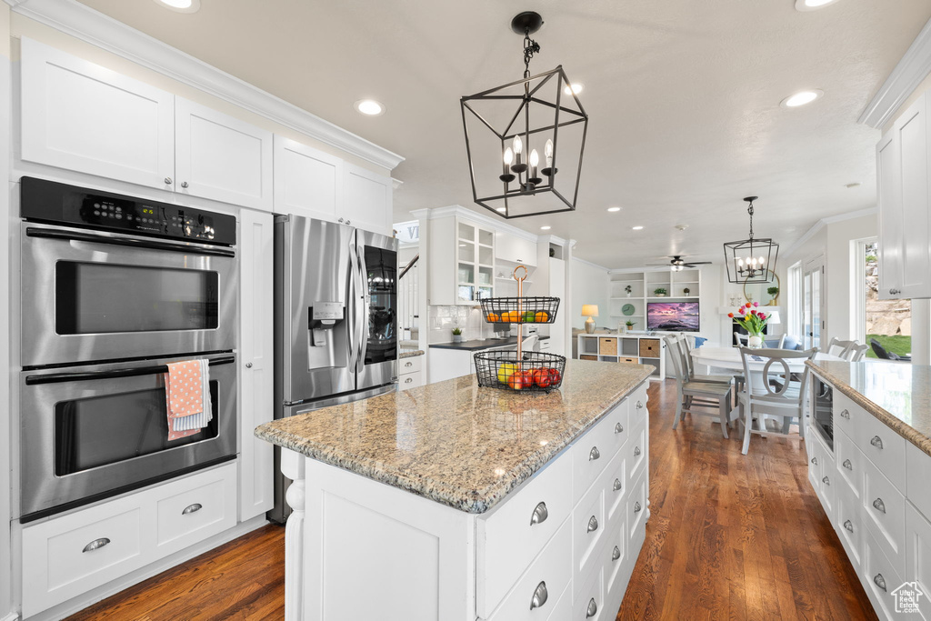 Kitchen with ornamental molding, stainless steel appliances, white cabinetry, and a kitchen island