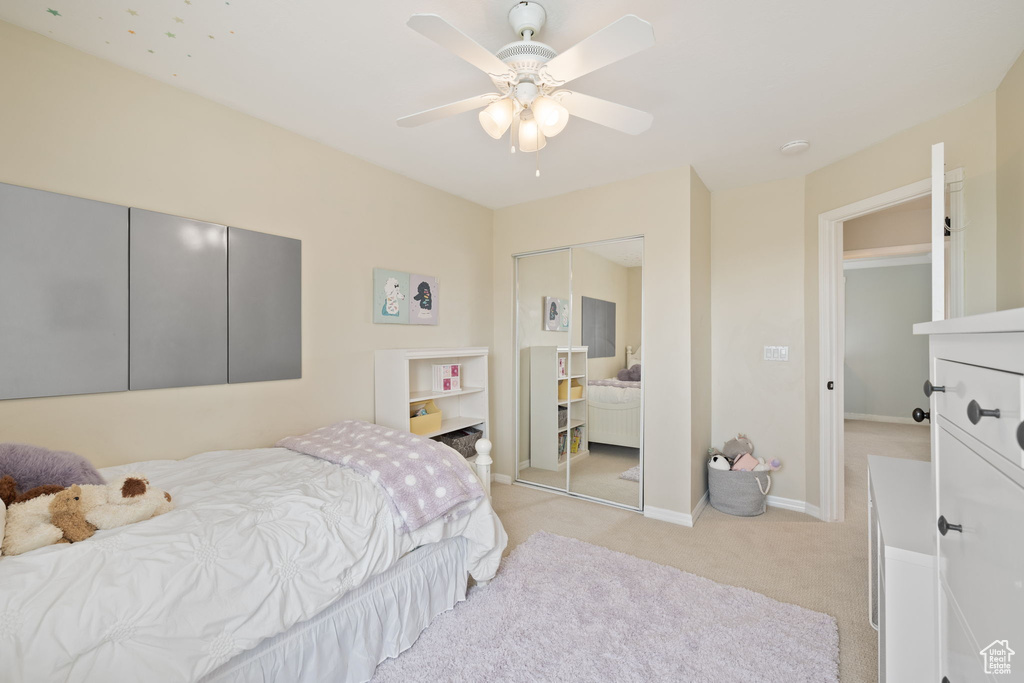 Bedroom featuring light colored carpet, baseboards, a ceiling fan, and a closet