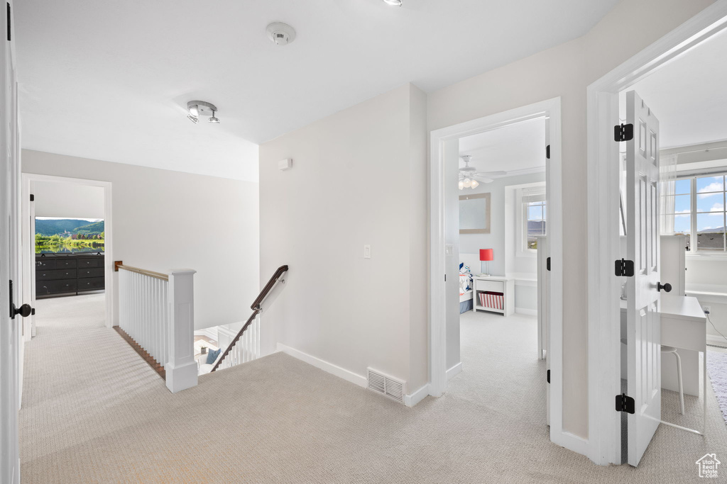 Hall featuring baseboards, visible vents, carpet floors, and an upstairs landing