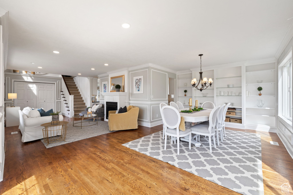 Dining space featuring recessed lighting, stairway, wood finished floors, a fireplace, and a notable chandelier