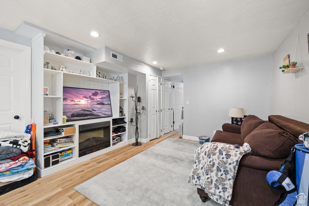 Living area featuring a textured ceiling, wood finished floors, visible vents, and recessed lighting