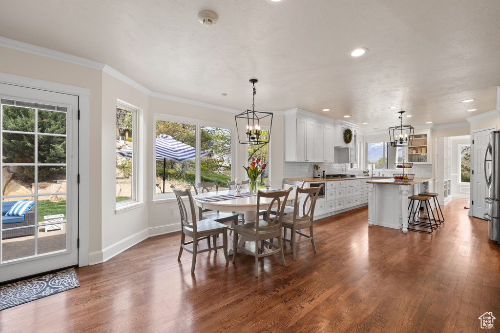 Dining area with crown molding, a chandelier, baseboards, dark wood-style flooring, and recessed lighting