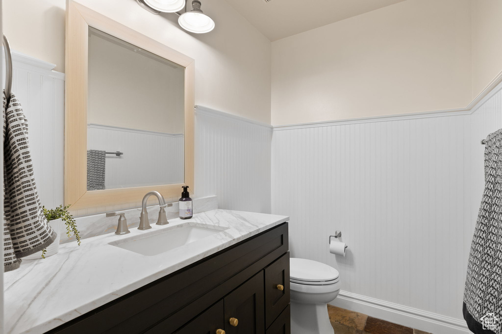 Bathroom featuring a wainscoted wall, vanity, and toilet