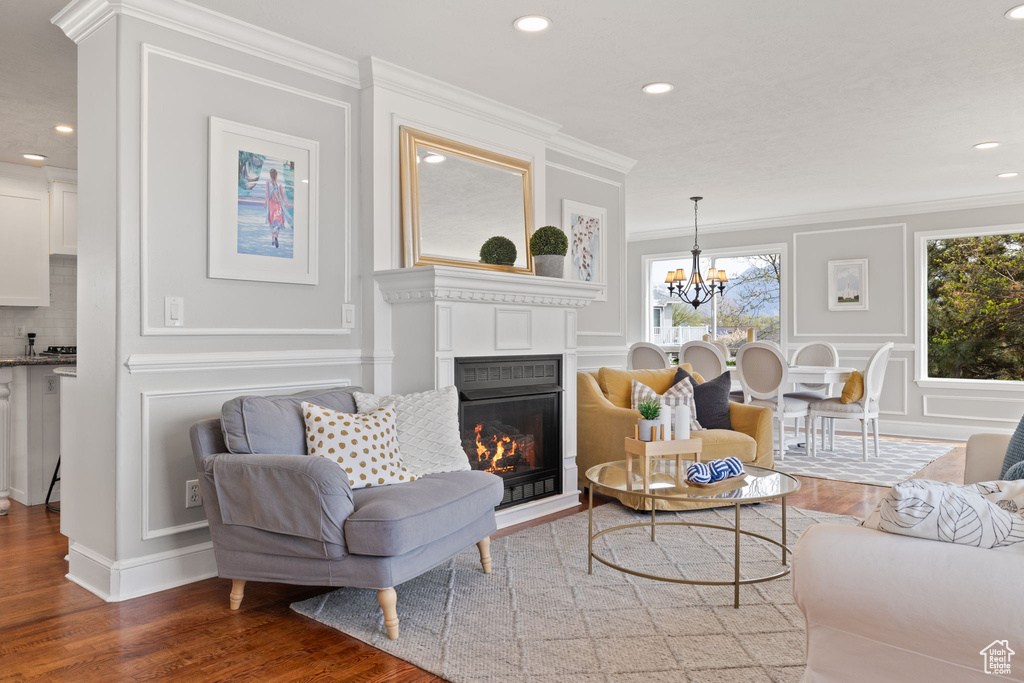 Living room featuring a decorative wall, crown molding, wood finished floors, and a wealth of natural light