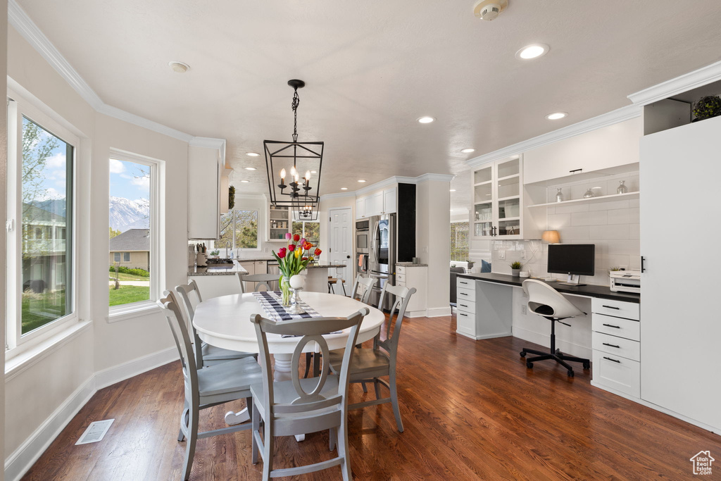 Dining space with plenty of natural light, a notable chandelier, crown molding, and dark wood-style flooring