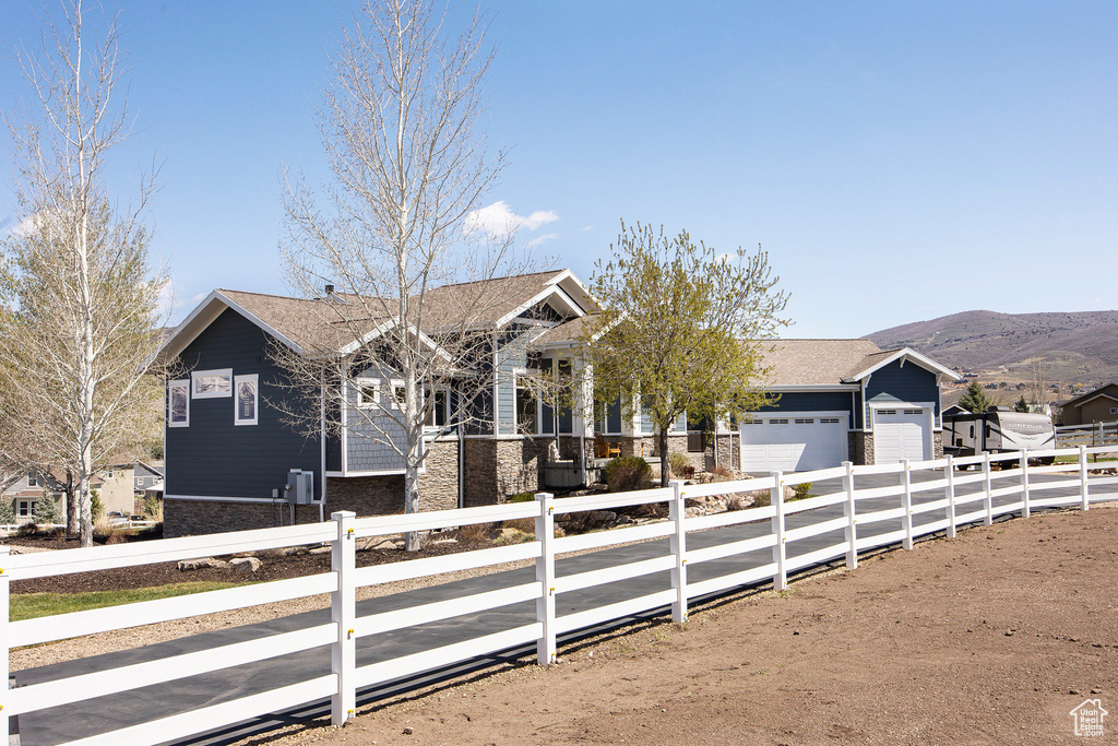 View of front facade with a garage, stone siding, concrete driveway, and a mountain view