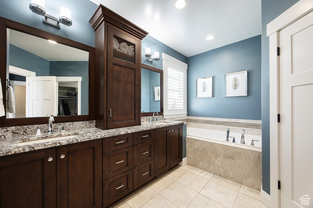 Bathroom featuring a bath, double vanity, and tile patterned floors