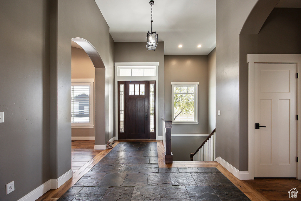 Foyer entrance featuring baseboards, plenty of natural light, arched walkways, recessed lighting, and stone tile flooring