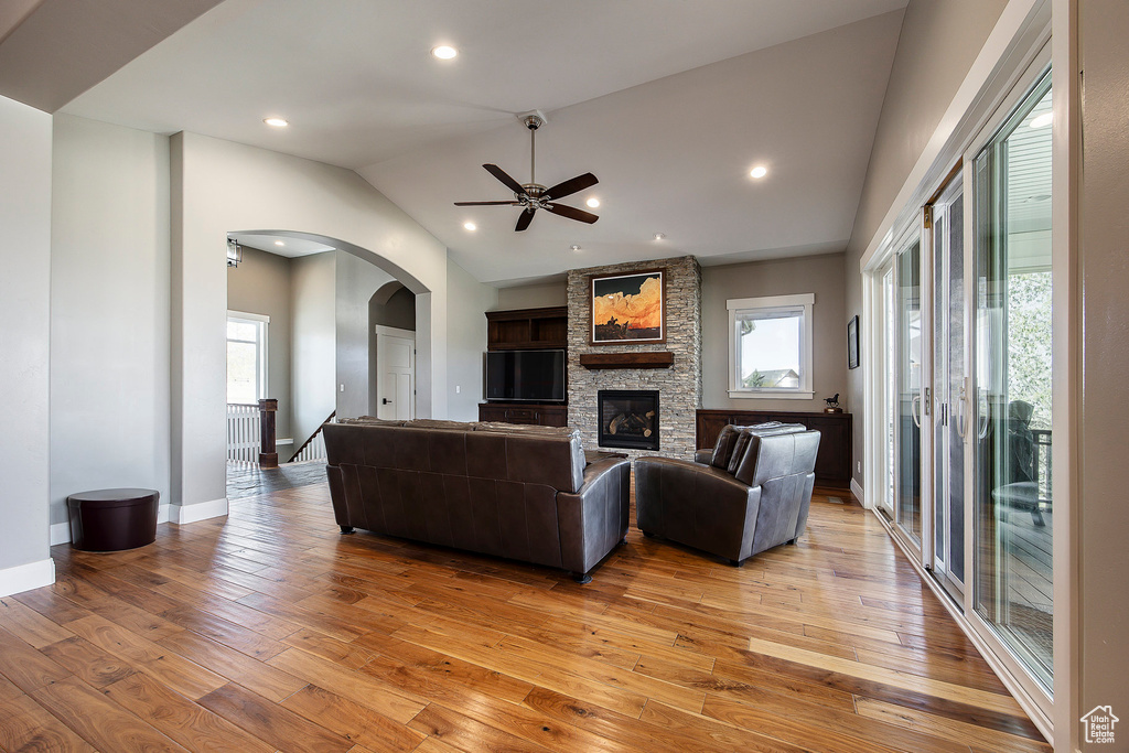 Living room featuring plenty of natural light, light wood-style floors, ceiling fan, arched walkways, and vaulted ceiling