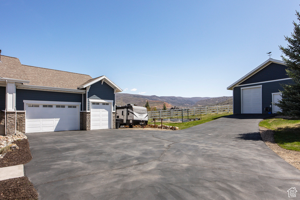 View of property exterior featuring a mountain view, stone siding, and asphalt driveway