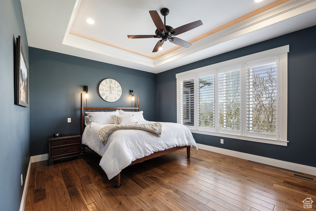 Bedroom featuring a raised ceiling, hardwood / wood-style floors, baseboards, recessed lighting, and a ceiling fan