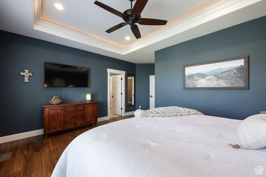 Bedroom featuring a tray ceiling, wood finished floors, baseboards, recessed lighting, and a ceiling fan