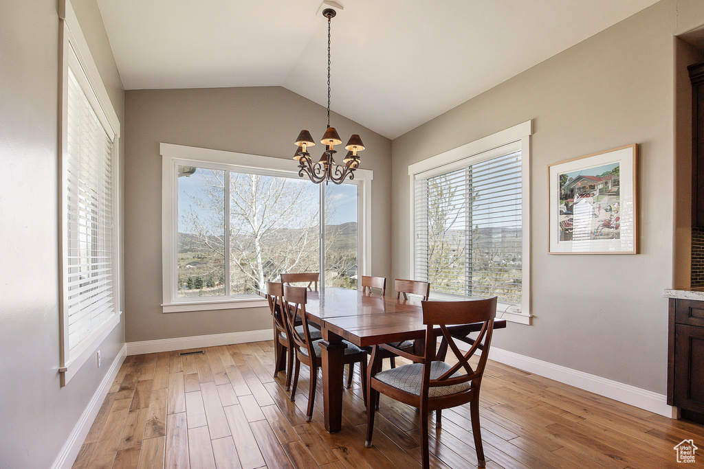 Dining space featuring light wood-style floors, a chandelier, baseboards, and lofted ceiling
