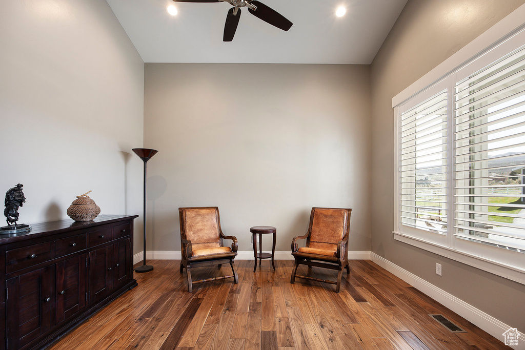 Sitting room with a ceiling fan, plenty of natural light, hardwood / wood-style floors, baseboards, and lofted ceiling