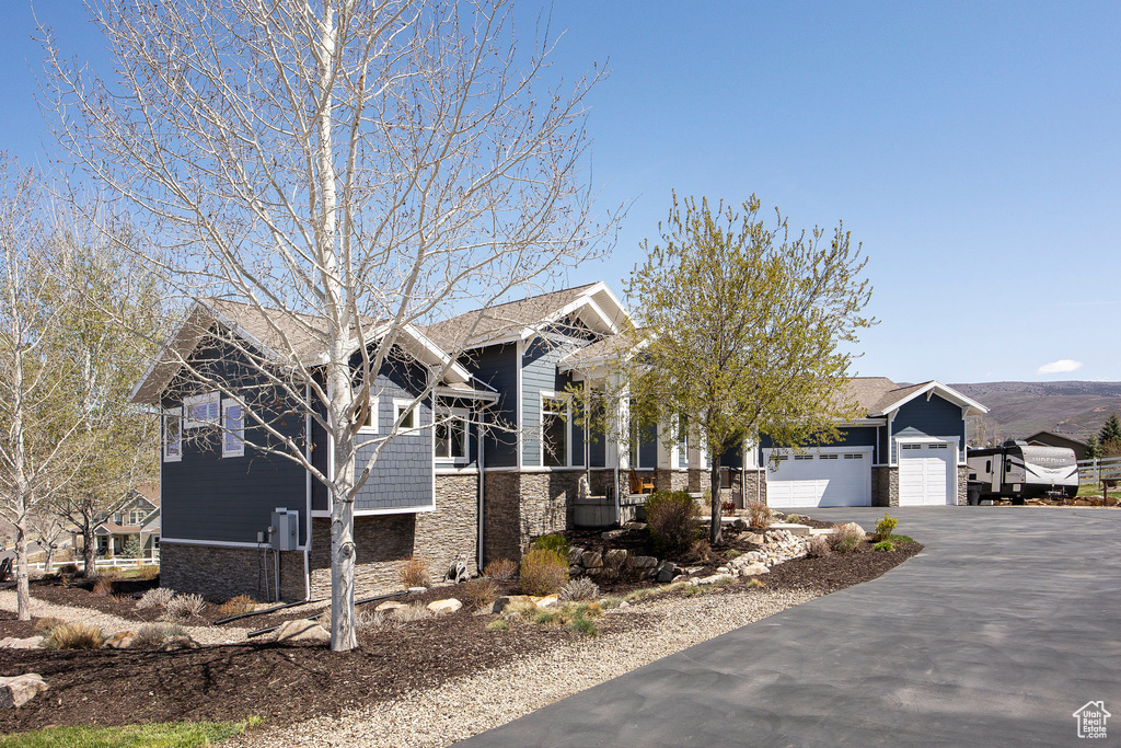 View of front of property with stone siding, a garage, and driveway