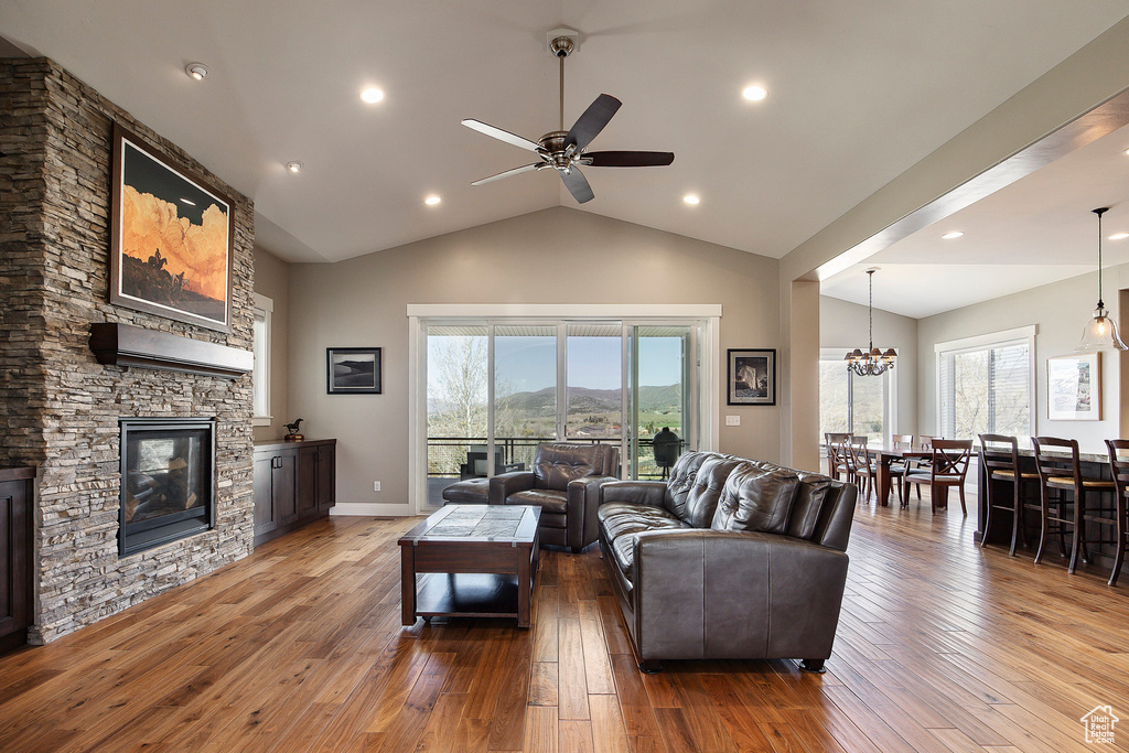 Living area featuring hardwood / wood-style floors, a ceiling fan, a stone fireplace, high vaulted ceiling, and healthy amount of natural light