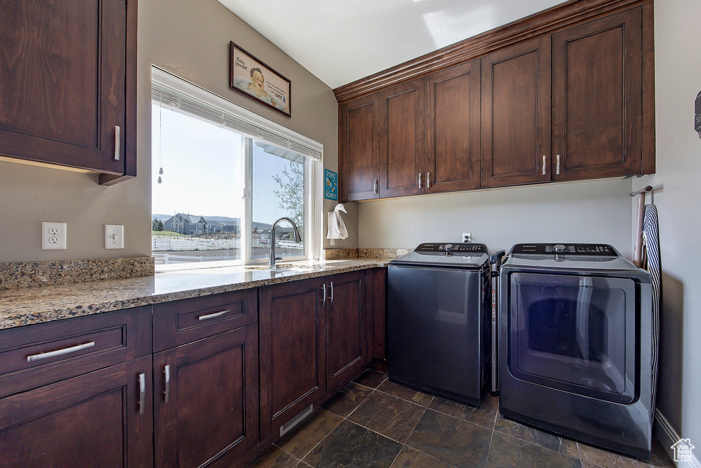 Laundry area with cabinet space, washing machine and clothes dryer, and dark stone finish floors