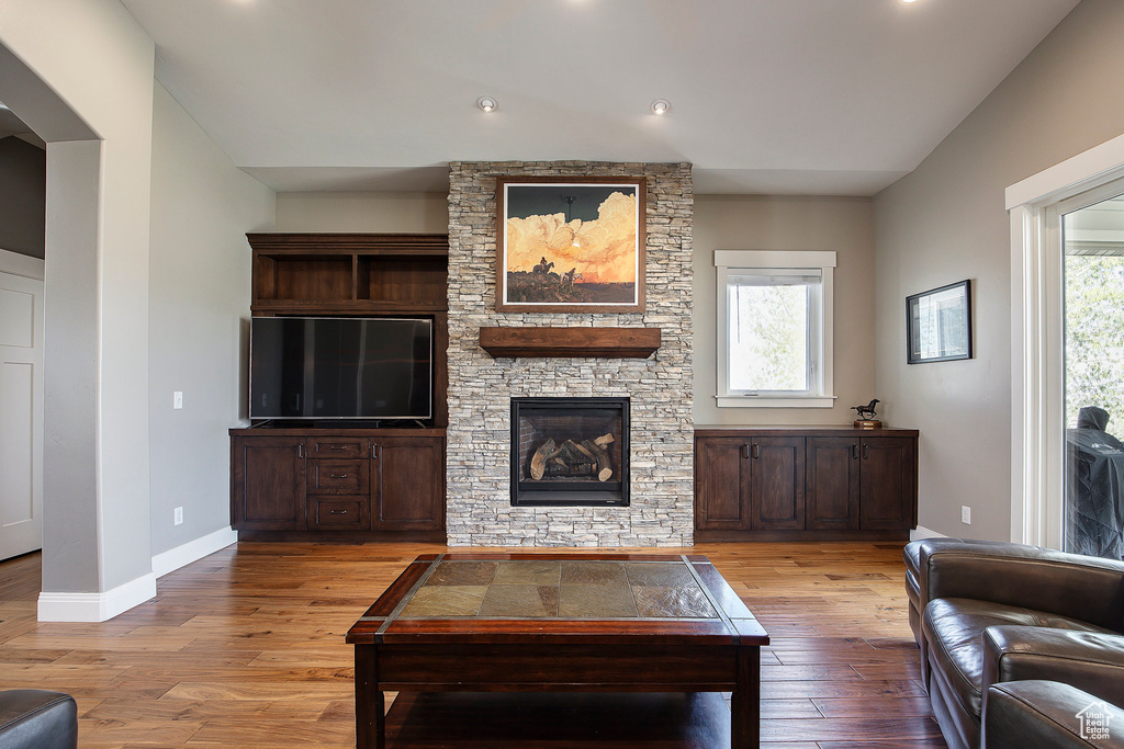 Living area featuring light wood-style floors, a stone fireplace, baseboards, and recessed lighting