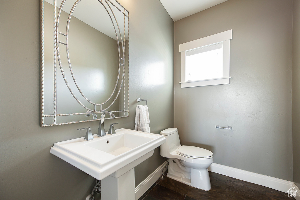 Bathroom with baseboards, toilet, and a sink