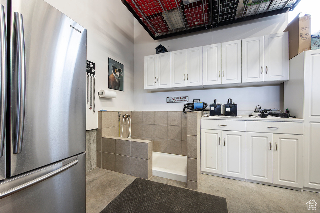 Kitchen with freestanding refrigerator, white cabinetry, and light countertops
