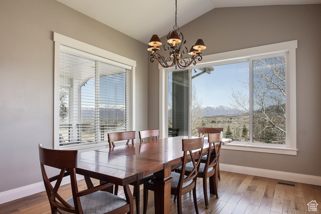 Dining room featuring lofted ceiling, baseboards, a chandelier, wood finished floors, and a mountain view