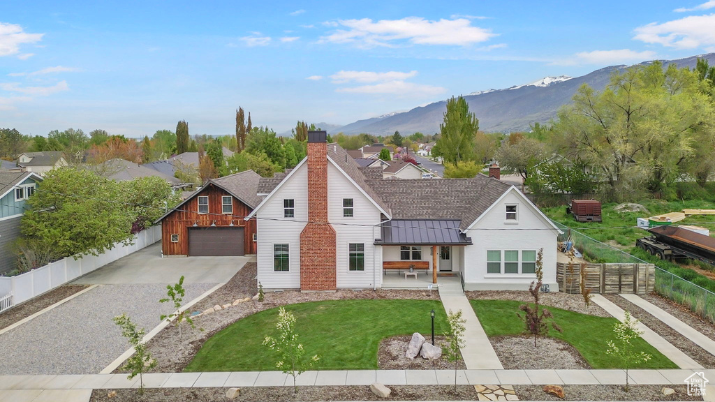 View of front of home with a standing seam roof, a mountain view, metal roof, concrete driveway, and fence