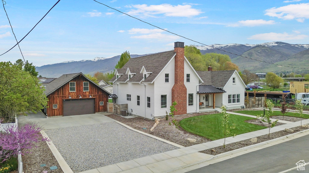 View of front of property featuring a chimney, a front lawn, a mountain view, fence, and gravel driveway
