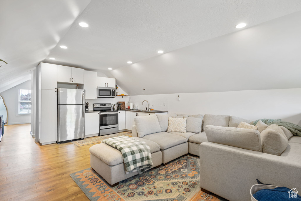 Living room featuring lofted ceiling, light wood-style floors, and recessed lighting