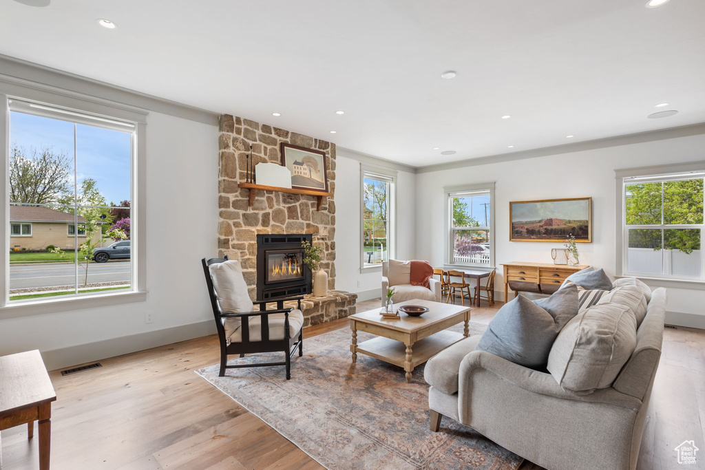 Living room with recessed lighting, a stone fireplace, visible vents, baseboards, and light wood-style flooring