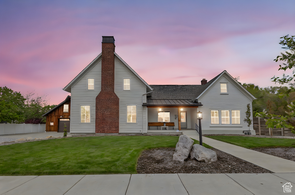 View of front facade featuring a porch, a standing seam roof, a chimney, and a front yard