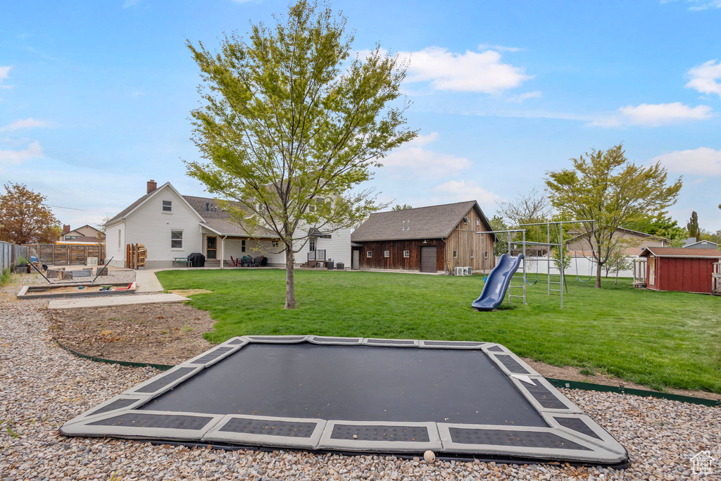 View of yard with a playground, fence, a patio area, an outdoor structure, and a shed