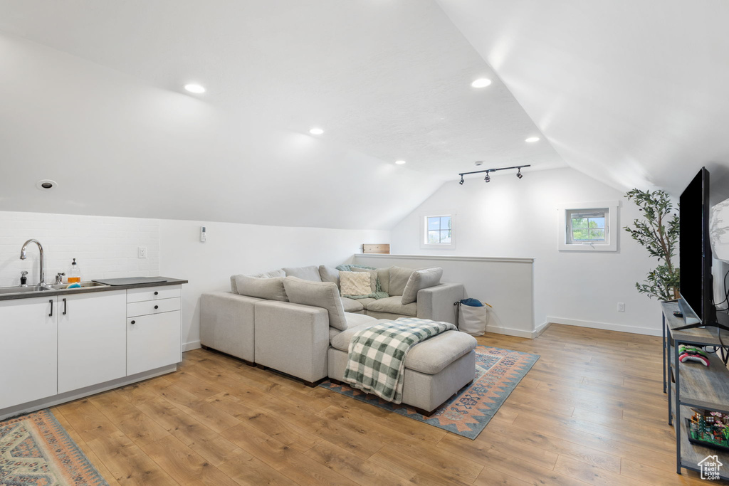 Interior space with baseboards, vaulted ceiling, light wood finished floors, and recessed lighting