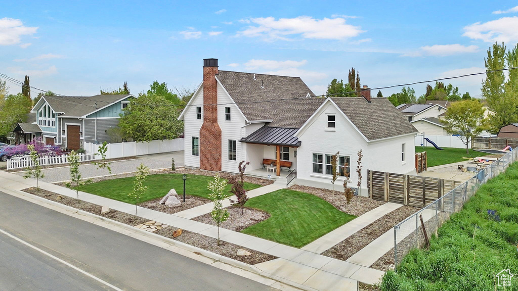 View of front of property with a fenced backyard, a chimney, a standing seam roof, and metal roof