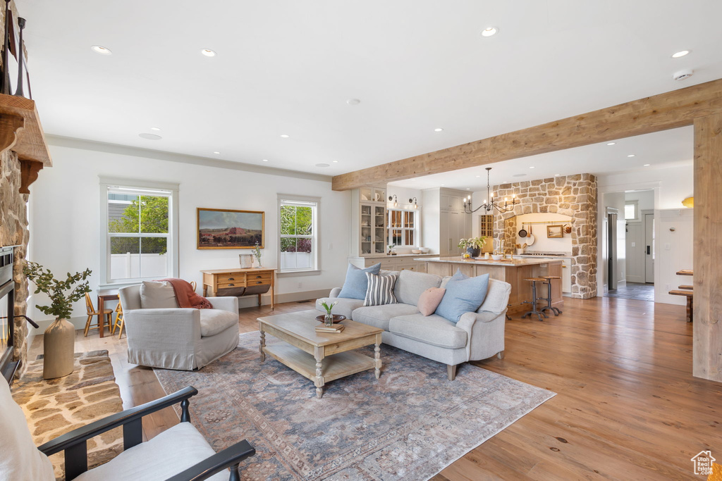 Living room featuring recessed lighting, light wood-style floors, baseboards, a fireplace, and a notable chandelier
