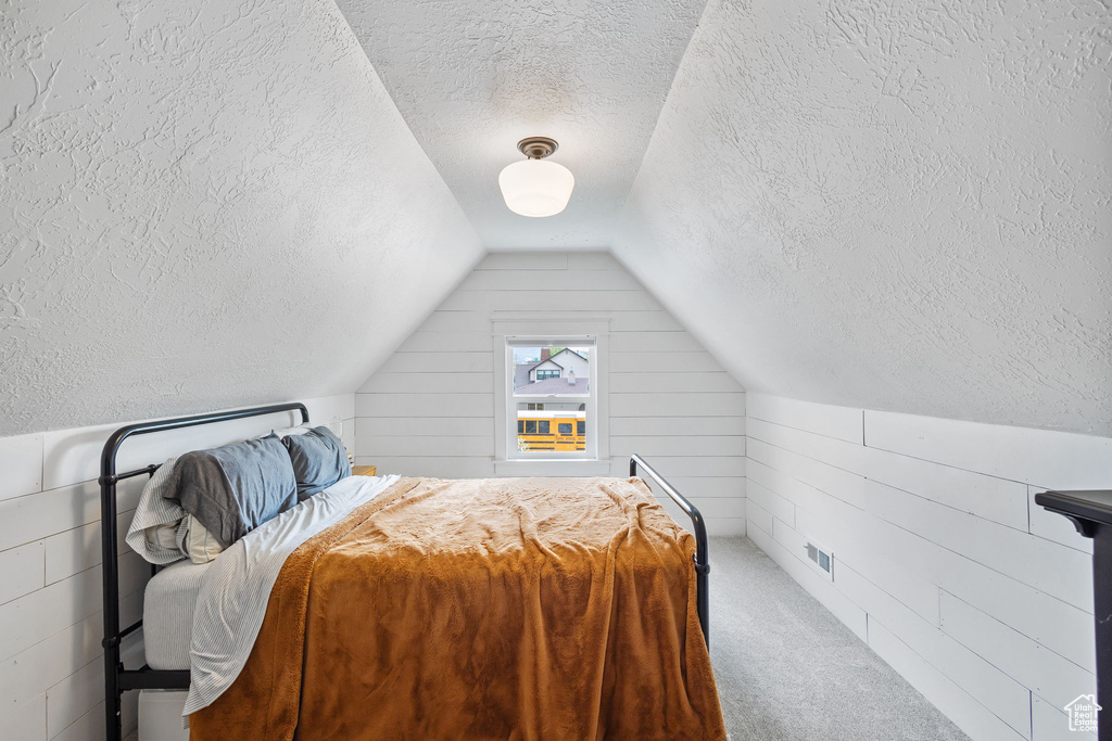Carpeted bedroom with vaulted ceiling and a textured ceiling