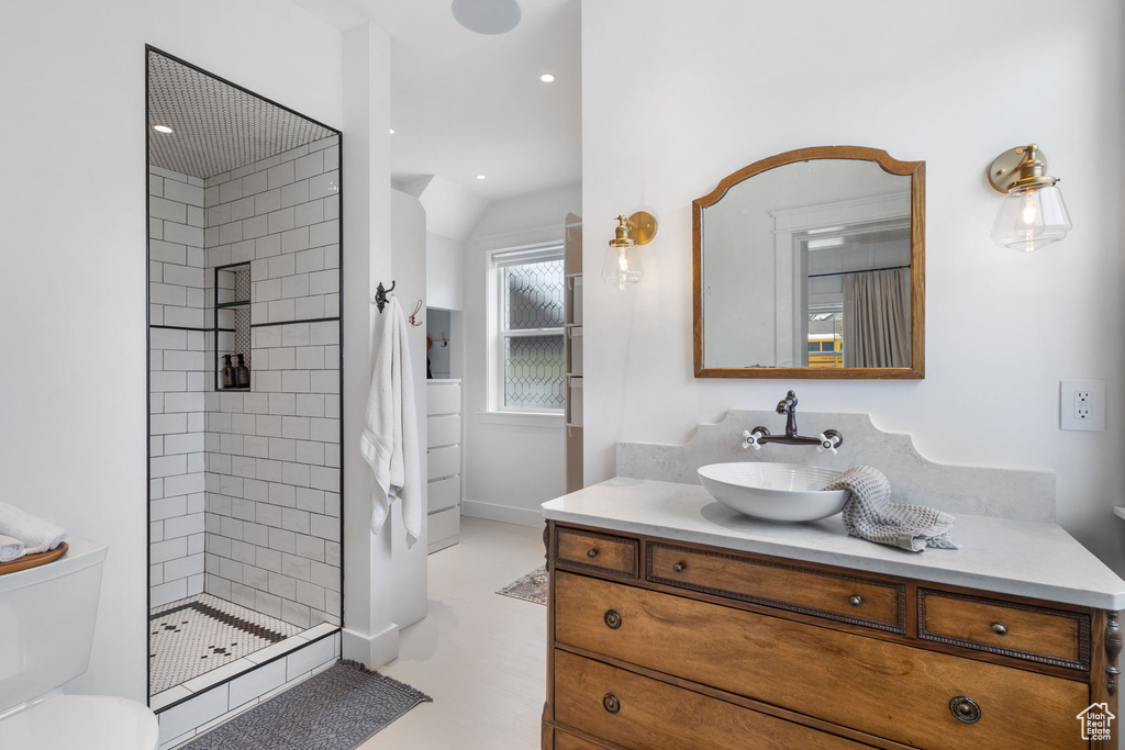 Bathroom with recessed lighting, toilet, vanity, baseboards, and tiled shower