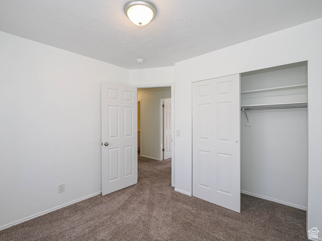 Unfurnished bedroom with baseboards, carpet flooring, and a closet
