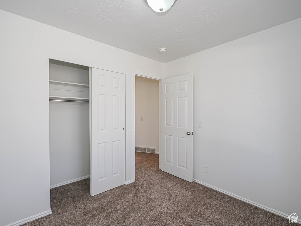Unfurnished bedroom featuring baseboards, carpet flooring, visible vents, and a closet