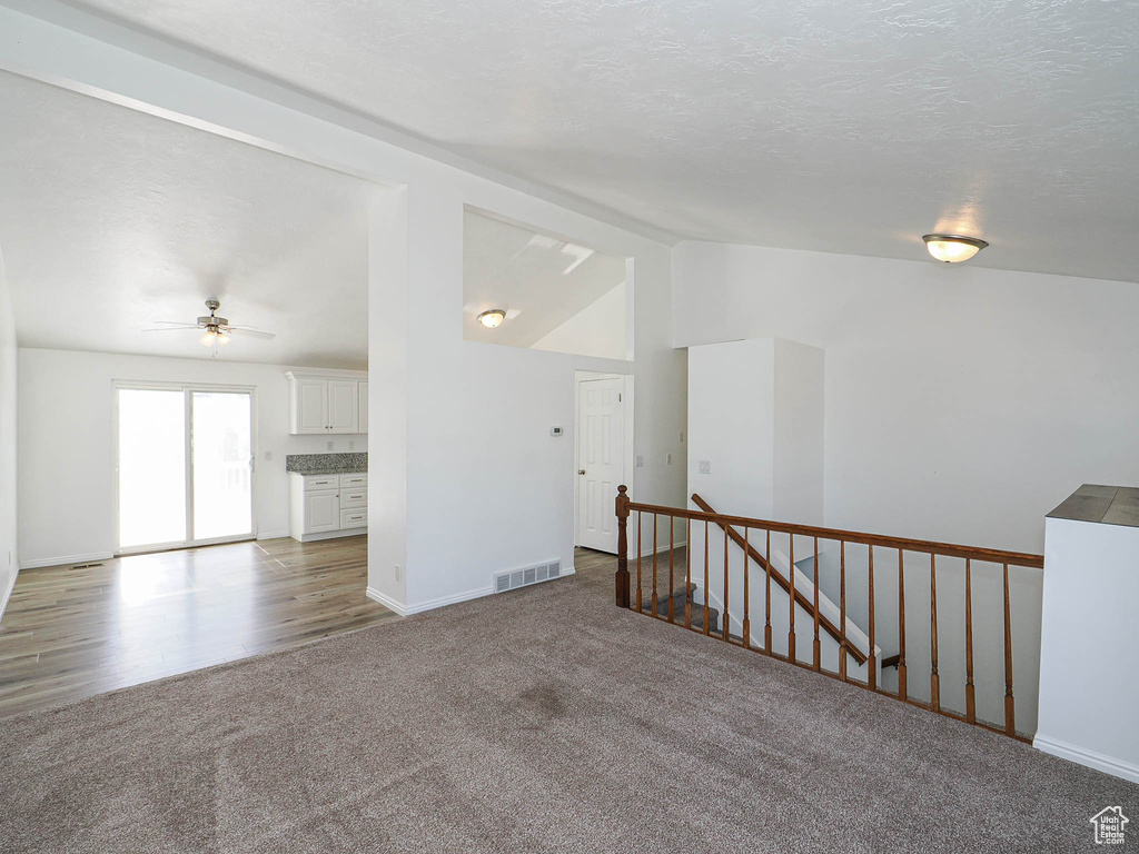 Spare room with a ceiling fan, baseboards, lofted ceiling, carpet flooring, and visible vents