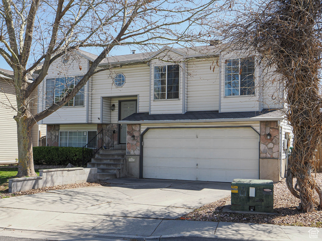 Split foyer home featuring a garage, driveway, and stone siding