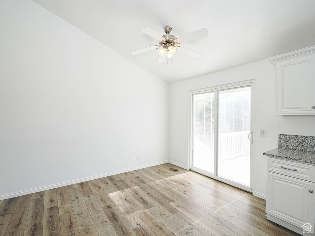 Unfurnished dining area featuring light wood-type flooring, lofted ceiling, baseboards, and ceiling fan